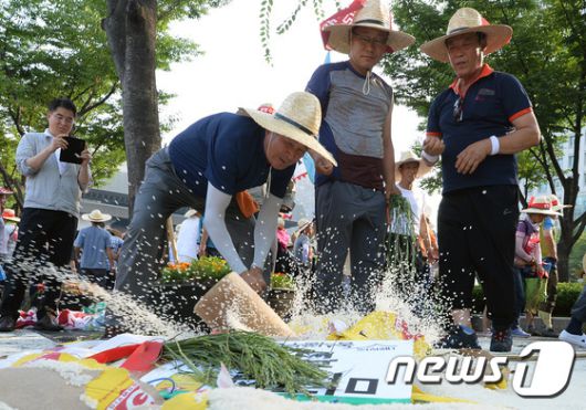 전국농민대회에 참가자들이 31일 오후 서울 세종로 정부서울청사 앞에서 밥쌀 수입 중단 촉구하며 미국산 쌀포대를 망치로 내리치고 있다. 농민들은 정부가 작년 9월 세계무역기구(WTO)에 쌀 관세화를 통보해 쌀 수입에 대한 의무가 끝났음에도 밥쌀 수입을 강행하고 있다며 밥쌀 수입을 중단하고 농민생존권을 보장하라고 촉구했다. 2015.7.31/뉴스1 ⓒ News1 신웅수 기자