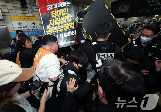 전국장애인차별철폐연대(전장연) 회원들이 21일 서울 지하철 4호선 혜화역 동대문 방면 승강장에서 제62차 '출근길 지하철 탑니다' 시위를 벌이던 중 이를 저지하던 경찰·서울교통공사 직원 등과 충돌하고 있다. 2025.4.21/뉴스1 ⓒ News1 이동해 기자