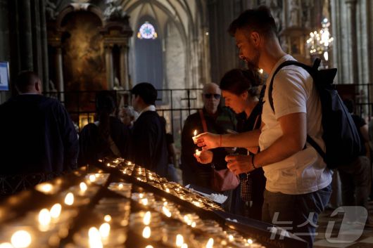 프란치스코 교황이 서거한 21일(현지시간) 비엔나의 성 스테판 대성당에서 열린 부활절 월요일 미사에서 사람들이 촛불을 켜고 있다. ⓒ AFP=뉴스1 ⓒ News1 김성진 기자