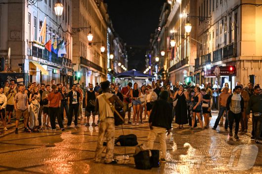 이베리아 반도에 대규모 정전이 발생한 가운데 28일(현지시간) 포르투갈 리스본 루아 아우구스타 거리에 조명이 복원되자 거리 예술가들이 연주를 하고 있다. ⓒ AFP=뉴스1