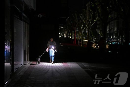 이베리아 반도에 대규모 정전이 발생한 28일(현지시간) 스페인 비고에서 한 시민이 어둠속에서 반려견과 산책을 하고 있다. ⓒ AFP=뉴스1