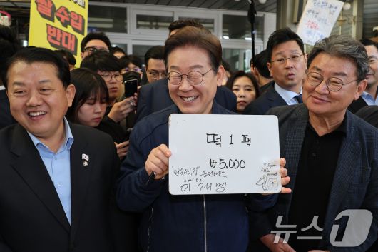 '골목골목 경청투어 : 접경벨트편'에 나선 이재명 더불어민주당 대통령 후보가 2일 오전 강원 철원군 동송전통시장에 위치한 떡집에 들러 가격판에 서명을 한 뒤 미소를 짓고 있다. (공동취재) 2025.5.2/뉴스1 ⓒ News1 이재명 기자