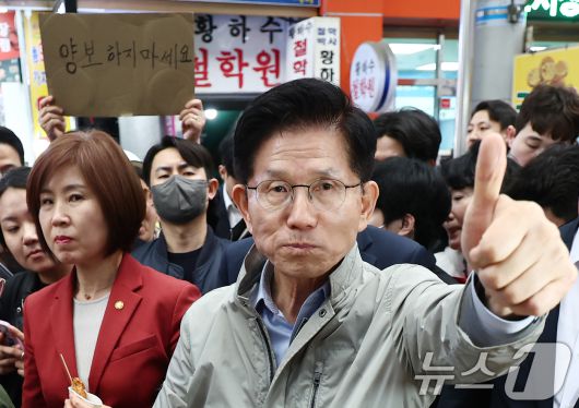 김문수 국민의힘 대통령 후보가 6일 경북 포항시 죽도시장에서 구매한 어묵을 먹으며 엄지를 치켜세우고 있다. 뒷편으로는 한 지지자가 '양보 하지 마세요'라고 적힌 종이를 들어보이고 있다. 2025.5.6/뉴스1 ⓒ News1 김민지 기자