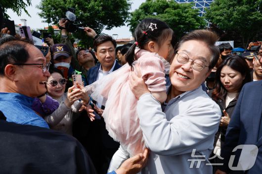 이재명 더불어민주당 대통령 후보가 2차 골목골목 경청투어 마지막 날인 7일 오후 전북 전주시 풍남문 앞에서 한 어린이를 안아들고 있다. 2025.5.7/뉴스1 ⓒ News1 안은나 기자