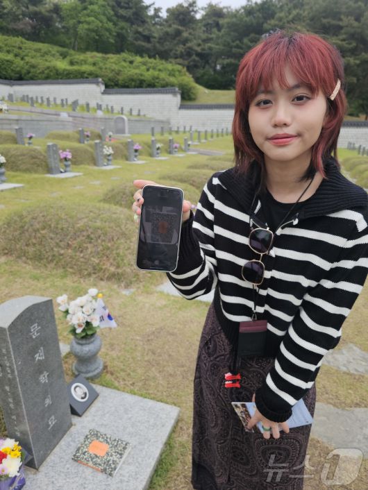11일 광주 북구 운정동 5·18민주묘역에서 태국 대학생 나띠씨가 소설 ‘소년이 온다’의 실제 모델인 문재학 군의 묘소에서 자신의 휴대폰 속 ‘소년이 온다’사진을 들어보이고 있다. 나띠씨는 한국 드라마 ‘오월의 청춘’을 시작으로 영화 ‘택시운전사’를 보고 5·18을 알게 됐다. 2025.5.11/뉴스1 ⓒ News1 서충섭 기자
