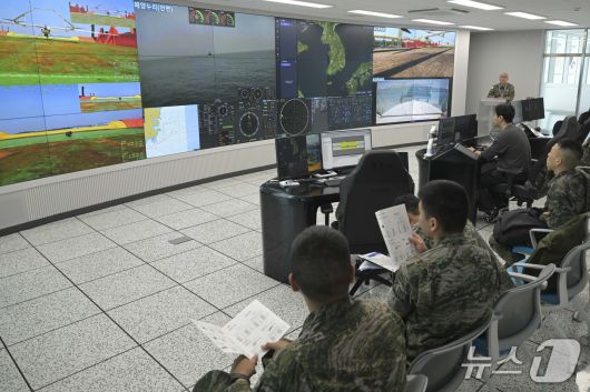 12일 울산 일산항 일대에서 진행된 해군 주관 '전·평시 상용 무인체계 작전 운용 가능성 검증훈련'에 참가한 민관군 훈련 관계관들이 자율운항선박성능실증센터 내 전시화면을 통해 훈련 진행상황을 지켜보고 있다.(해군 제공)