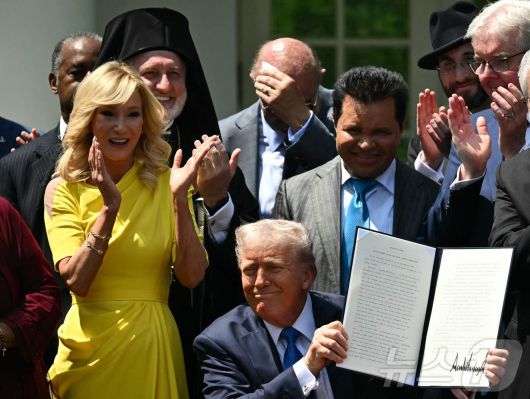 도널드 트럼프 미국 대통령이 지난 5월 1일(현지시간) 워싱턴 백악관에서 열린 '국가 기도의 날' 행사 중 대통령 직속으로 '종교 자유 위원회'를 설치하는 행정명령을 들고 있다. 2025.05.02 ⓒ AFP=뉴스1 ⓒ News1 우동명 기자