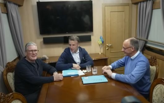 에마뉘엘 마크롱 프랑스 대통령이 영국, 독일 정상들과의 기차 회담에서 테이블의 휴지를 치우려는 모습. 유튜브 화면 갈무리. 2025.05.13.