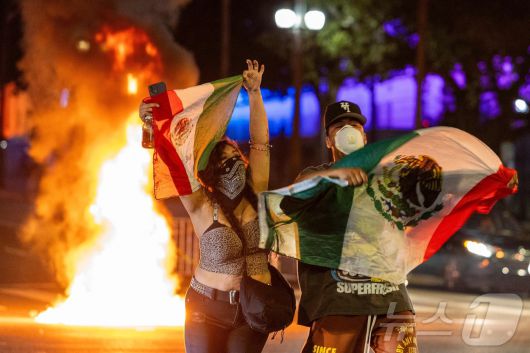 8일(현지시간) 미국 캘리포니아주 로스앤젤레스(LA) 시내에서 연방 이민 단속에 반대하는 시위 중 시위대가 멕시코 국기를 들고 있다. 2025.6.8 ⓒ AFP=뉴스1 ⓒ News1 김경민 기자