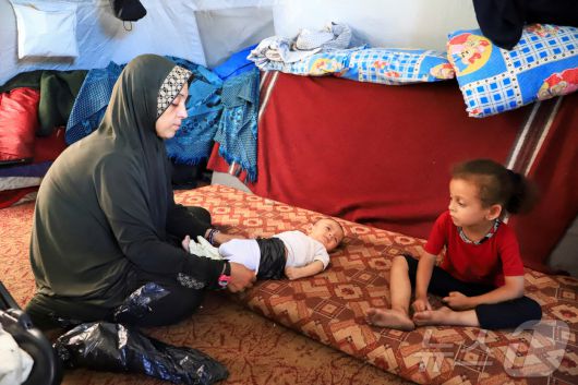 25일(현지시간) 팔레스타인 가자 지구의 한 어머니가 2개월된 쌍둥이 중 한 명을 수심에 찬 얼굴로 바라보고 있다. 가자 지구는 분유와 기저귀가 매우 부족한 상황이다.2025.06.25. ⓒ 로이터=뉴스1 ⓒ News1 권영미 기자