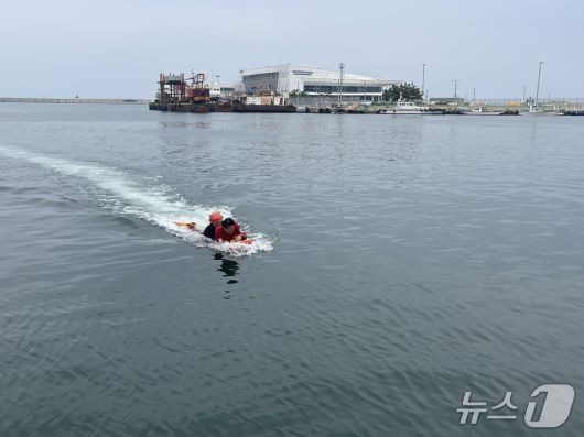 지난 7일 오후 강원 속초 속초해경 전용부두 인근 해상에서 진행된 구조·구급 대응 훈련에 동참한 기자. 결국 요구조자가 돼 구조대원에 이끌려 물 밖으로 나오고 있다.(속초해경 제공, 재판매 및 DB 금지) 2025.7.8/뉴스1
