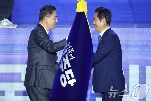 정청래 더불어민주당 신임 당대표가 2일 경기 고양시 킨텍스에서 열린 제2차 임시전국당원대회에서 김병기 원내대표로 부터 당기를 이양받고 있다. 2025.8.2/뉴스1 ⓒ News1 유승관 기자