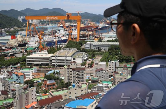 대미 수출 관세 인하와 조선업 투자를 골자로 한 한미 무역 협상이 타결된 31일 한 시민이 경남 거제시 아주동 주거단지 너머로 한화오션 거제사업장 대형 크레인을 바라보고 있다. 정부는 미국 도널드 트럼프 행정부와 무역 협상 합의에는 한국이 제안한 조선업 협력안인 '마스가'(MASGA) 프로젝트가 가장 크게 기여했다고 밝혔다. 2025.7.31/뉴스1 ⓒ News1 윤일지 기자