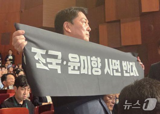 안철수 국민의힘 당대표 후보가 15일 오전 서울 종로구 세종문화회관에서 열린 제80주년 광복절 경축식에 참석해 경축사 중인 이재명 대통령을 향해 조국 전 조국혁신당 대표와 윤미향 전 의원의 사면 반대 플래카드를 들어보이며 항의하고 있다. (안철수 캠프 제공) 2025.8.15/뉴스1