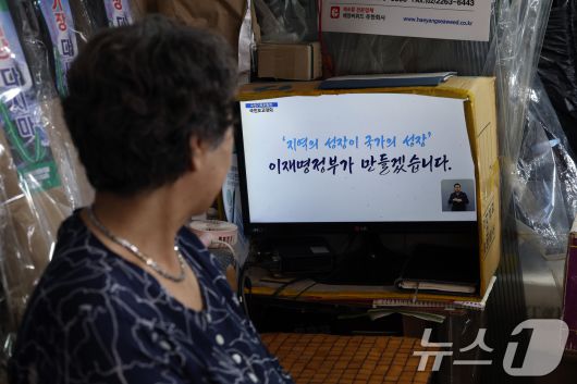 13일 오후 서울 도심의 한 전통시장에서 상인이 국정기획위원회 국민보고대회 '국민이 주인인 나라 함께 행복한 대한민국’ 생중계를 지켜보고 있다. 2025.8.13/뉴스1 ⓒ News1 박정호 기자