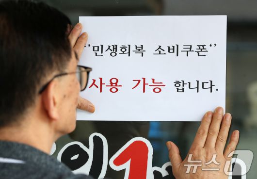 지난 7월22일 대구 중구의 한 음식점 사장이 출입문에 민생회복 소비쿠폰 사용 가능 안내문을 붙이고 있다. 2025.7.22/뉴스1 ⓒ News1 공정식 기자