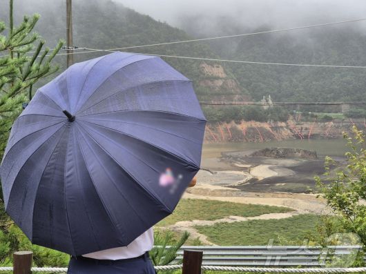 극심한 가뭄을 겪고 있는 강원 강릉지역에 많은 비가 내린 13일 오전 우산을 쓴 시민이 마른 저수지에 내리는 단비를 바라보고 있다. 2025.9.13/뉴스1 ⓒ News1 윤왕근 기자