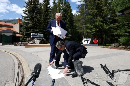 키어 스타머 영국 총리가 2025년 6월 16일 캐나다 앨버타주 캐내내스키스에서 열린 주요 7개국(G7) 정상회의 도중, 도널드 트럼프 미국 대통령이 기자들과 이야기하는 동안 떨어뜨린 서류를 주워주고 있다. 2025.6.16 ⓒ 로이터=뉴스1 ⓒ News1 강민경 기자