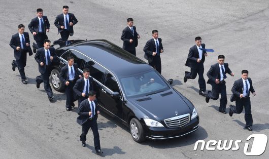 김정은 국무위원장이 27일 판문점 평화의 집에서 문재인 대통령과 오전 정상회담을 마치고 북측으로 가기 위해 차를 타고 이동하고 있다. 12명의 경호원들이 김 위원장의 차량을 에워싼 채 이동하고 있다. 2018.4.27/뉴스1 ⓒ News1 한국공동사진기자단