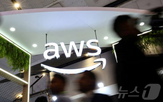 인도 아마존웹서비스. FILE PHOTO: People walk past the logo of Amazon Web Services (AWS) at its exhibitor stall at the India Mobile Congress 2025 at Yashobhoomi, a convention and expo center in New Delhi ⓒ 로이터=뉴스1