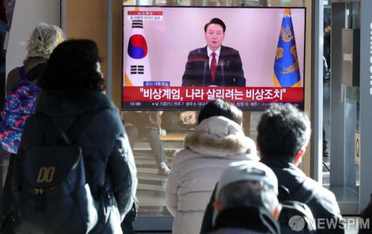 [서울=뉴스핌] 최지환 기자 = 12일 오전 서울 용산구 서울역에서 시민들이 윤석열 대통령의 긴급 성명 발표를 지켜보고 있다. 2024.12.12 choipix16@newspim.com