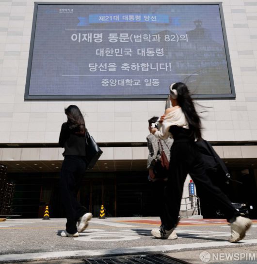 [서울=뉴스핌] 류기찬 인턴기자 = 이재명 대통령의 취임 첫날인 4일 오후 서울 동작구 중앙대학교에 이재명 대통령의 당선을 축하하는 문구가 전광판에 표시되는 가운데 시민들이 이동하고 있다.  2025.06.04 ryuchan0925@newspim.com