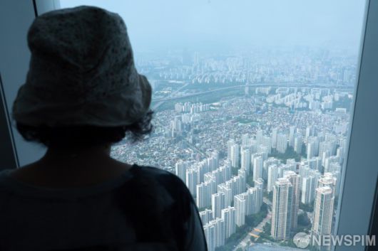 [서울=뉴스핌] 이길동 기자 = 서울 부동산 시장이 들썩이고 있다.18일 서울 송파구 롯데월드타워 서울스카이에서 한 시민이 잠실 일대 아파트을 바라보고 있다. 서울 주택매매 심리지수는 과열 구간에 근접했다. 국토연구원이 17일 발표한 '5월 부동산시장 소비심리지수'에 따르면 지난달 전국 주택매매시장 소비심리지수는 113.0으로 전월보다 4.3포인트(p) 올랐는데, 서울이 131.5로 가장 큰 상승 폭(11p)으로 반등을 주도했다. 2025.06.18 gdlee@newspim.com