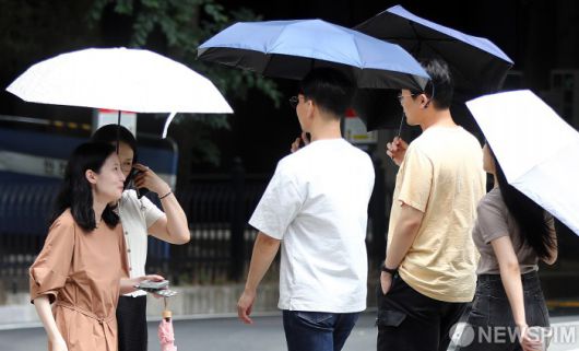[서울=뉴스핌] 이형석 기자 = 무더위가 이어지며 체감온도가 33도를 넘나드는 1일 오후 서울 여의도 인근에서 시민들이 양산을 쓰고 발걸음을 재촉하고 있다. 2025.07.01 leehs@newspim.com
