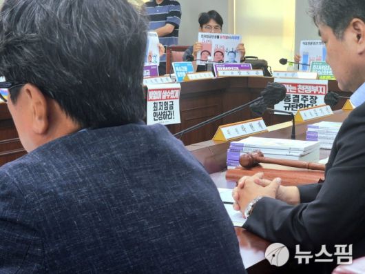 [세종=뉴스핌] 양가희 기자 = 10일 정부세종청사에서 열린 최저임금위원회 제12차 전원회의에서 공익위원 간사 권순원 숙명여대 교수(왼쪽)와 이인재 최저임금위원회 위원장(오른쪽) 사이로 장도준 근로자위원(가운데)이 윤석열 정부 첫 해 최저임금 인상률보다 이재명 정부 인상률이 낮다는 내용의 그래프가 인쇄된 종이를 들고 있다. 2025.07.10 sheep@newspim.com