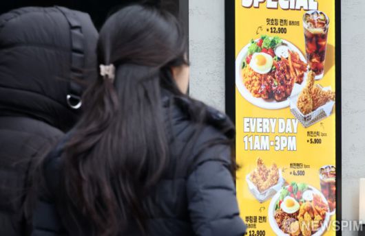 [서울=뉴스핌] 최지환 기자 = 정부가 상위 10대 치킨 프랜차이즈를 대상으로 매장 및 배달 주문 메뉴판에 조리 전 닭고기 무게를 고지해야 되는 '치킨 중량표시제'를 실시한 15일 서울 시내의 한 치킨매장 앞으로 시민들이 오가고 있다. 2025.12.15 choipix16@newspim.com