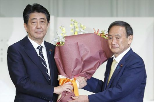 지난 9월 14일 총재 경선이 끝난 뒤 스가 신임 자민당 총재로부터 꽃다발을 받는 아베 신조 총리. (사진=연합뉴스)