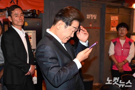 이재명 더불어민주당 대선 후보가 1일 서울 종로구의 한 음식점에서 열린 비전형 노동자 간담회 종료 후 당 관계자에게 전달받은 휴대전화를 확인하고 있다. 황진환 기자