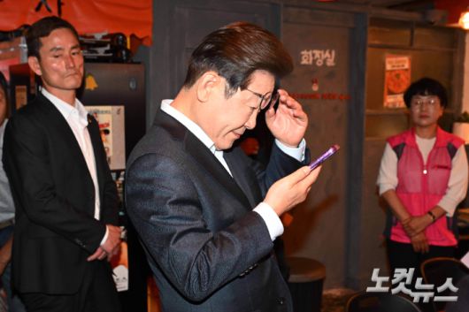 이재명 더불어민주당 대선 후보가 1일 서울 종로구의 한 음식점에서 열린 비전형 노동자 간담회 종료 후 당 관계자에게 전달받은 휴대전화를 확인하고 있다. 대법원 전원합의체는 이날 이 후보에게 무죄를 선고한 원심판결을 파기하고 사건을 서울고법으로 돌려보냈다. 황진환 기자