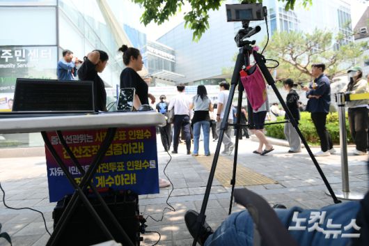 제21대 대통령선거 사전투표 이틀째인 30일 서울 강남구 역삼1동주민센터에 마련된 사전투표소 앞에서 부정선거 감시단이라고 주장하는 단체가 부정선거 감시와 계수를 명분으로 투표 대기 유권자들을 촬영하고 있다. 박종민 기자