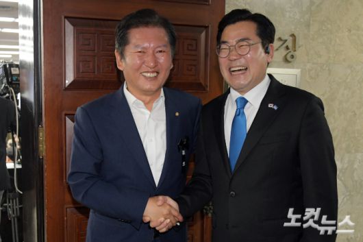 더불어민주당 당대표 출마를 선언한 정청래(왼쪽)·박찬대 의원이 24일 서울 여의도 국회에서 열린 당 의원총회에서 손을 잡고 환하게 웃고 있다. 윤창원 기자