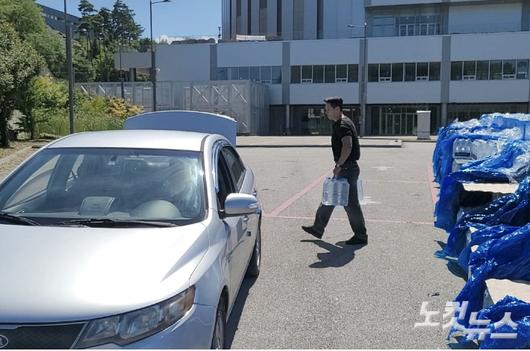 5일 오후 강릉시 스피드스케이팅경기장 주차장에 마련한 '드라이브 스루'를 통해 생수를 받으러 온 차량에 유원들이 생수를 싣고 있는 모습. 전영래 기자