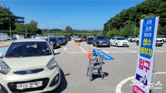 지난 5일 오후 강릉시 스피드스케이팅경기장 주차장에 마련한 '드라이브 스루'를 통해 생수를 받으러 온 차량들이 늘어선 모습. 전영래 기자