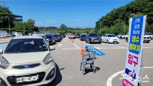 지난 5일 오후 강릉시 스피드스케이팅경기장 주차장에 마련한 '드라이브 스루'를 통해 생수를 받으러 온 차량들이 늘어선 모습. 전영래 기자