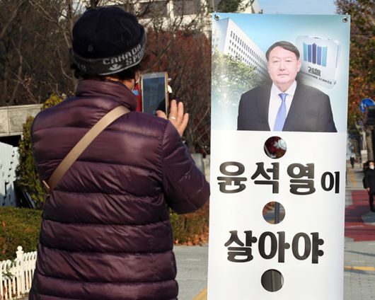 26일 서울 서초구 대검찰청 앞에서 한 시민이 윤석열 검찰총장의 모습이 나온 배너를 휴대전화 카메라로 찍고 있다. 연합뉴스