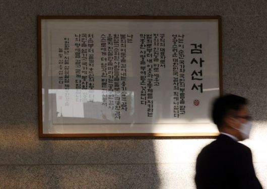 윤석열 검찰총장의 직무 집행정지 처분에 반대하는 검찰의 집단행동이 이어지고 있는 가운데 27일 오전 서울 서초구 서울중앙지검 청사에 걸린 검사선서 앞으로 관계자가 지나가고 있다. 연합뉴스