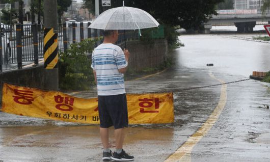 지난 7월 14일 대전 중구 선화동 현암교 인근 하천변 수위가 높아져 인근 하상도로가 잠긴 가운데, 한 시민이 내리는 비를 지켜보고 있다. 연합뉴스