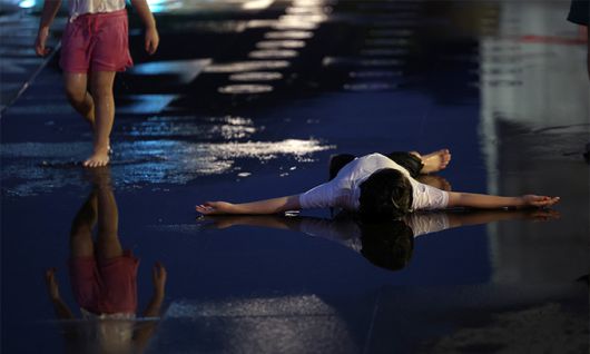 지난 13일 서울 광화문광장 분수대에서 분수 가동을 기다리며 어린이가 더위를 식히고 있다. 연합뉴스