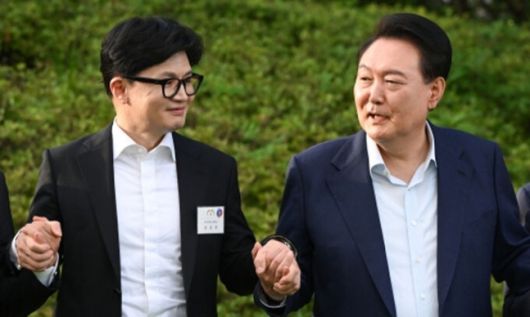 윤석열 대통령이 지난해 7월 24일 서울 용산 대통령실 앞 파인그라스에서 열린 국민의힘 신임 지도부 만찬에서 당시 한동훈 대표(왼쪽)와 손을 맞잡고 기념 촬영을 하고 있다. 연합뉴스