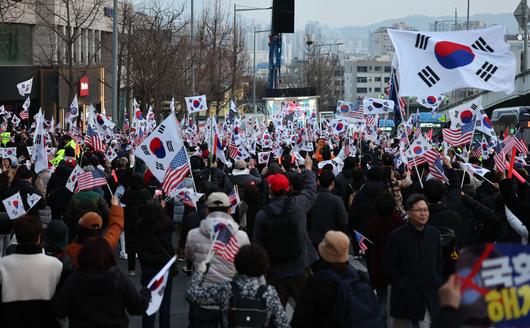 윤석열 대통령이 서울구치소에서 석방돼 한남동 관저로 돌아온 8일 윤 대통령 지지자들이 관저 앞에서 태극기를 흔들고 있다. 연합뉴스