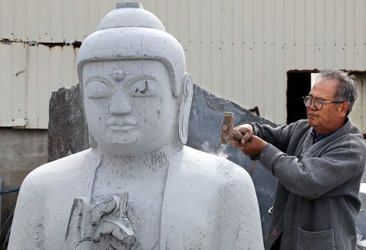 약사여래불 조성 중인 고석산 석장이 도드락망치질을 하며 표면을 고르고 있다.