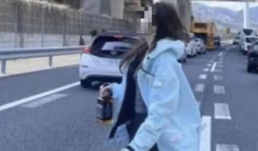 버스 충돌 사고로 통제된 고속도로에서 중국인 여성이 위스키를 들고 인증 사진을 찍고 있다. FNN 캡처