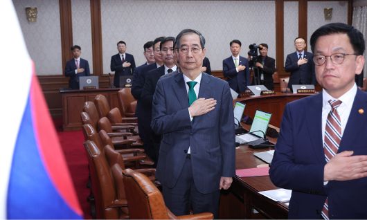 한덕수 대통령 권한대행 국무총리가 18일 정부서울청사에서 열린 추가경정예산안 심의 임시국무회의에서 국기에 경례하고 있다. 오른쪽은 최상목 경제부총리 겸 기획재정부 장관. 뉴시스