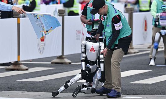 일부는 제대로 달리지 못해 한 로봇이 중심을 잃고 쓰러지자 관계자들이 일으켜 세우고 있다. 베이징=AFP연합뉴스