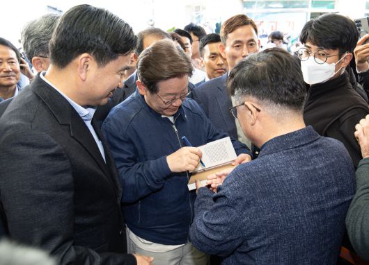 '골목골목 경청투어 : 접경벨트편'에 나선 이재명 더불어민주당 대통령 후보가 2일 오후 강원 인제군 북면 원통시장에서 한 지지자 요청으로 책에 서명하고 있다.   뉴스1