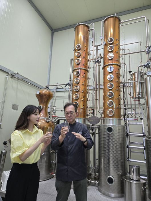 방송인 김민아와 오규섭 온 증류소 대표가 증류기를 통해 바로 나온 연연 25의 원주(알코올 90도 이상)를 맛보고 있다. 온 증류소 제공